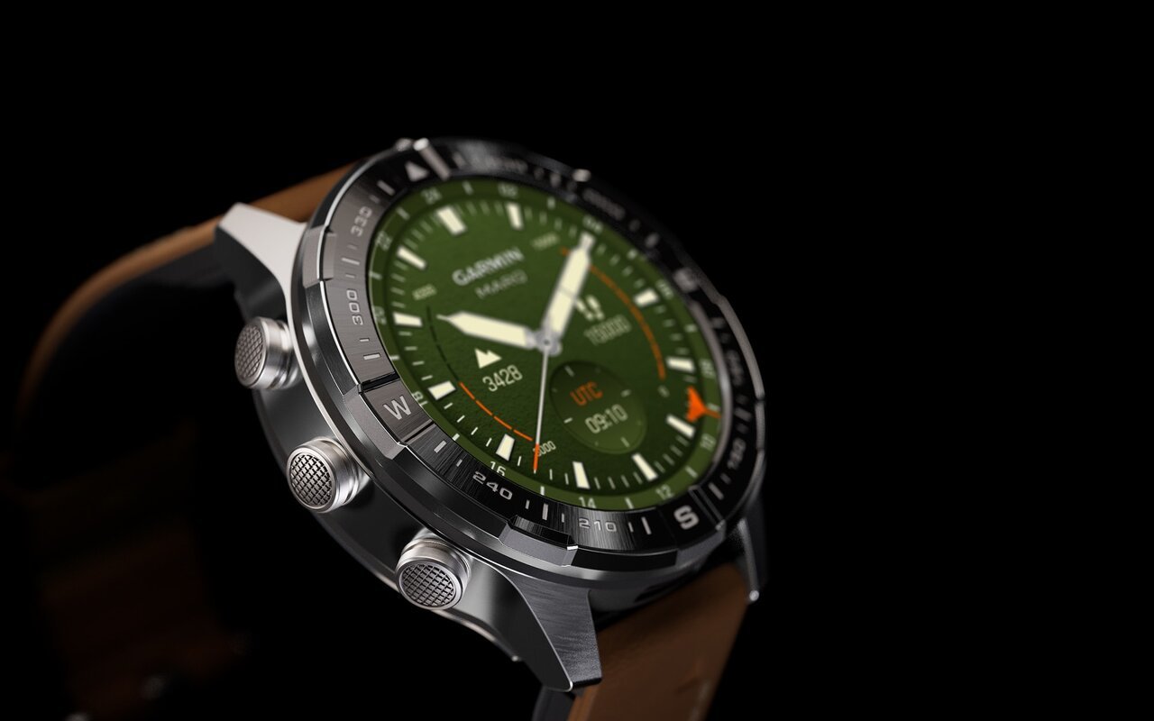 Montre connectée Garmin MARQ Adventurer Gen 3 vue de trois quarts, boîtier en titane brossé, lunette noire graduée en points cardinaux, cadran vert avec aiguilles et index luminescents, bracelet en cuir brun, sur fond noir