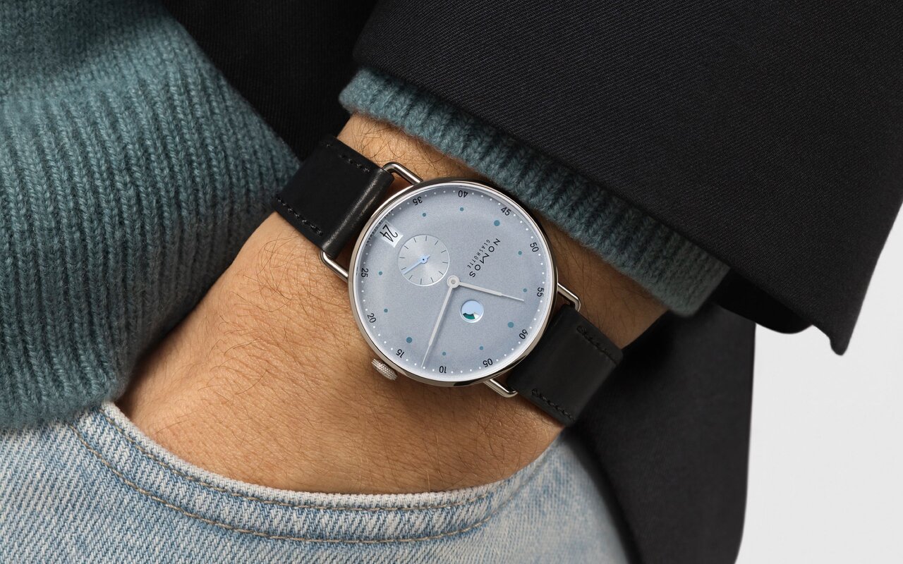 Montre Nomos Metro portée au poignet, cadran bleu glacier à points d'heures bleu canard, petite seconde, guichet de date et bracelet en cuir noir